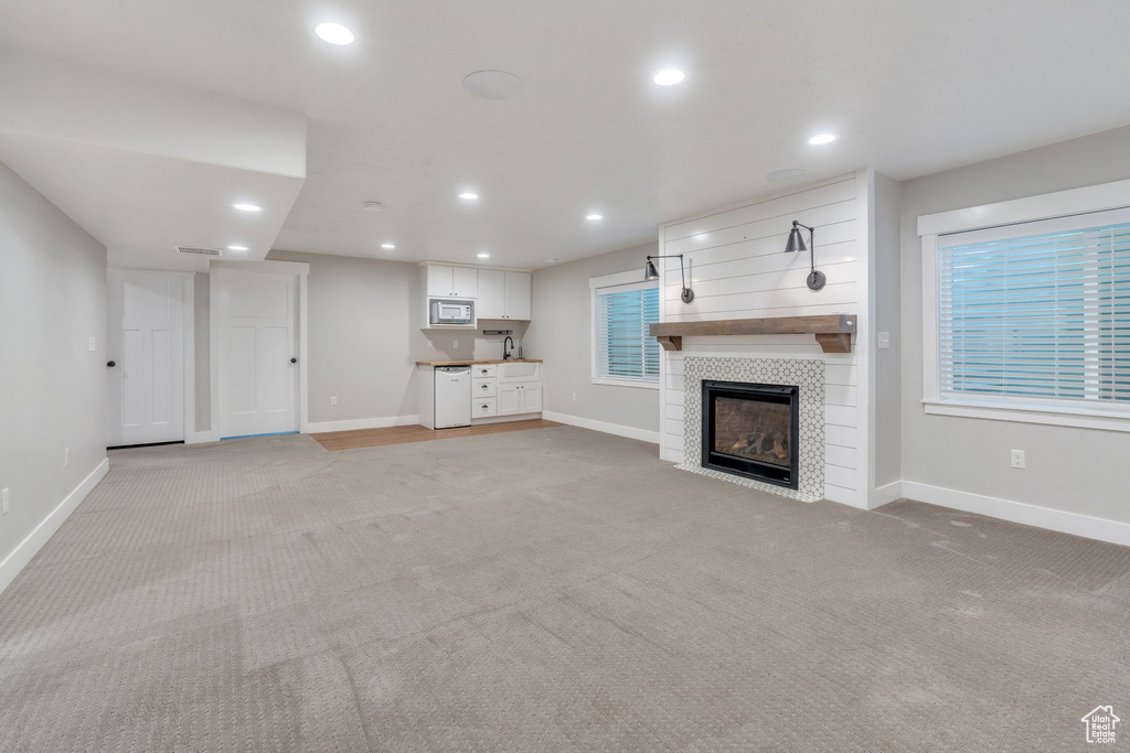 Unfurnished living room with light colored carpet, a fireplace, baseboards, and recessed lighting