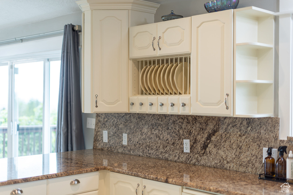 Kitchen featuring open shelves, decorative backsplash, and dark stone countertops