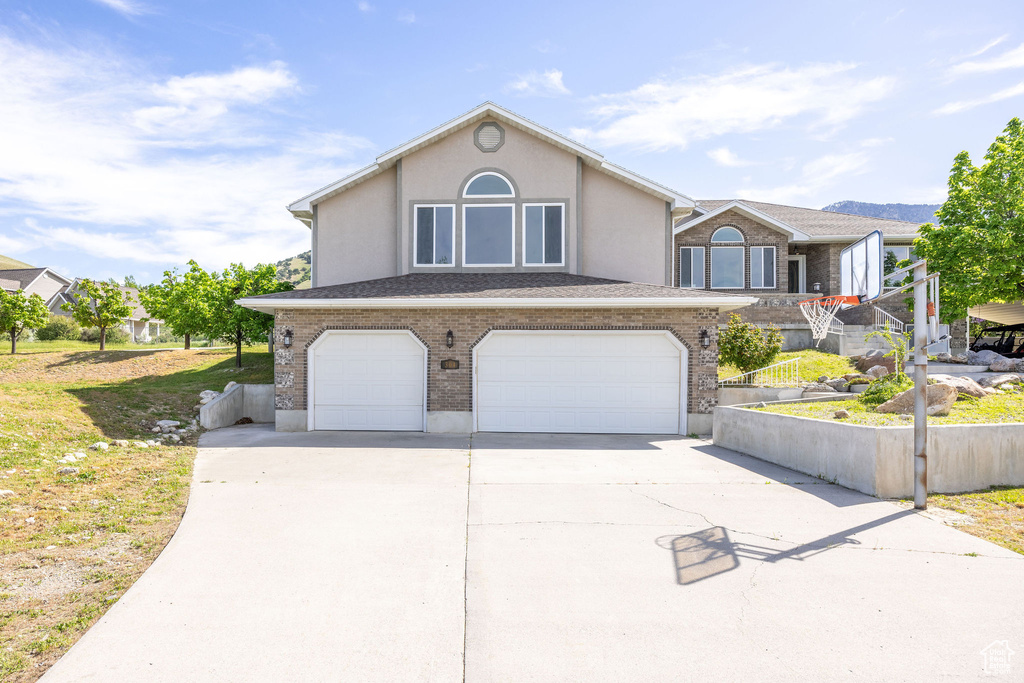 View of front facade with an attached garage, driveway, stucco siding, and brick siding