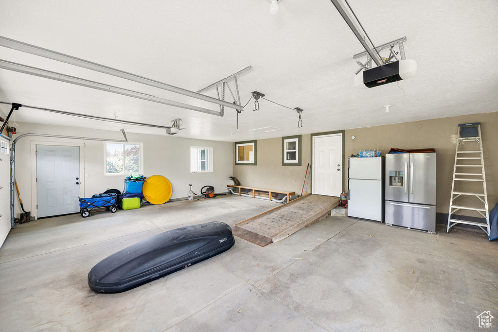 Garage featuring freestanding refrigerator, stainless steel fridge, and a garage door opener