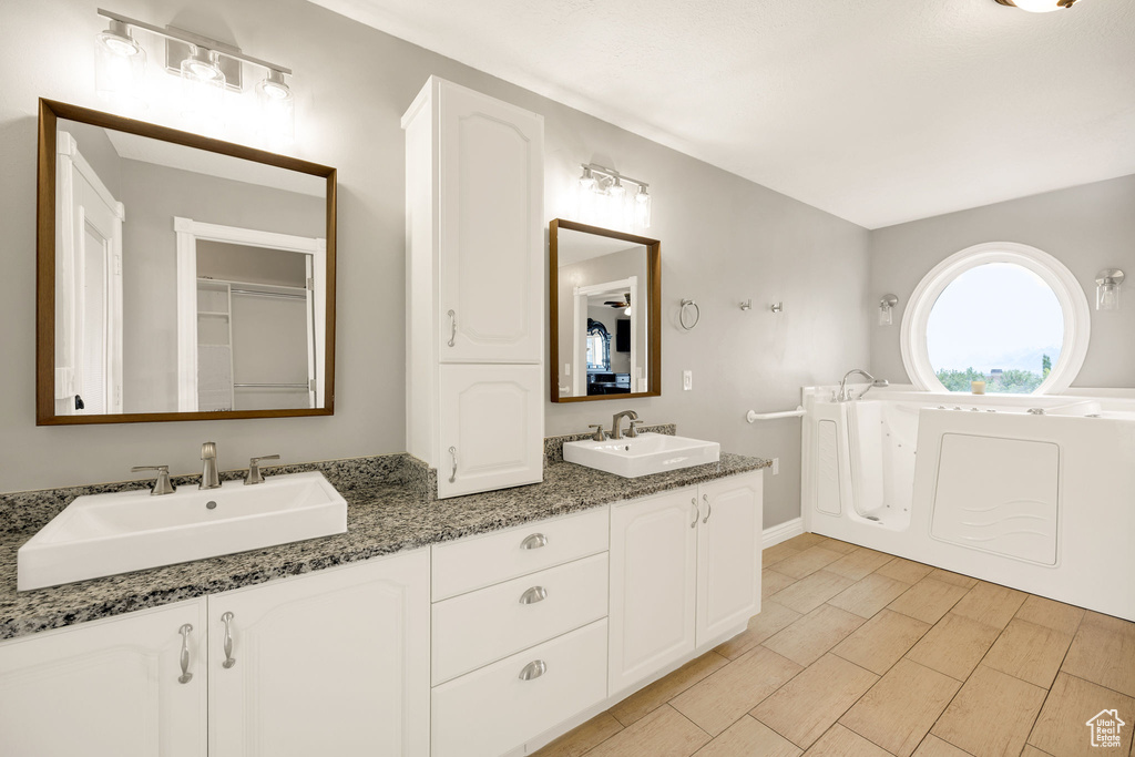 Bathroom featuring double vanity, baseboards, and a bathtub