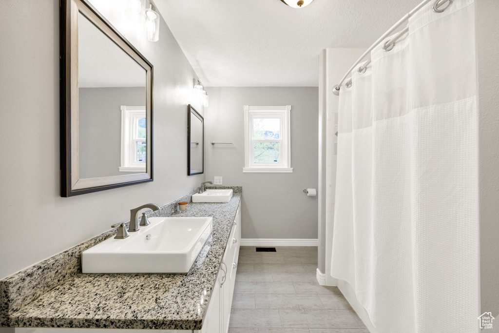 Full bathroom featuring double vanity and baseboards