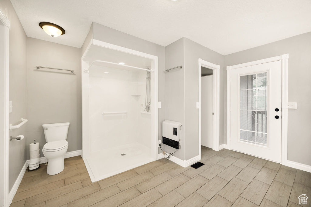 Full bathroom with heating unit, wood tiled floors, a shower stall, and baseboards