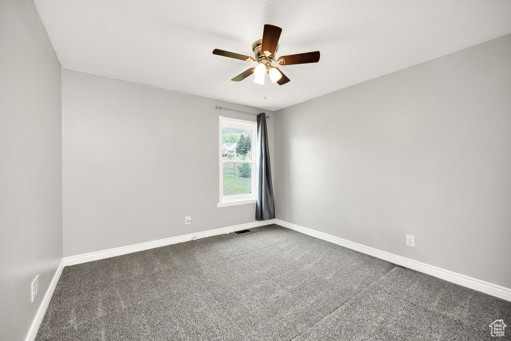 Spare room featuring carpet, baseboards, and a ceiling fan