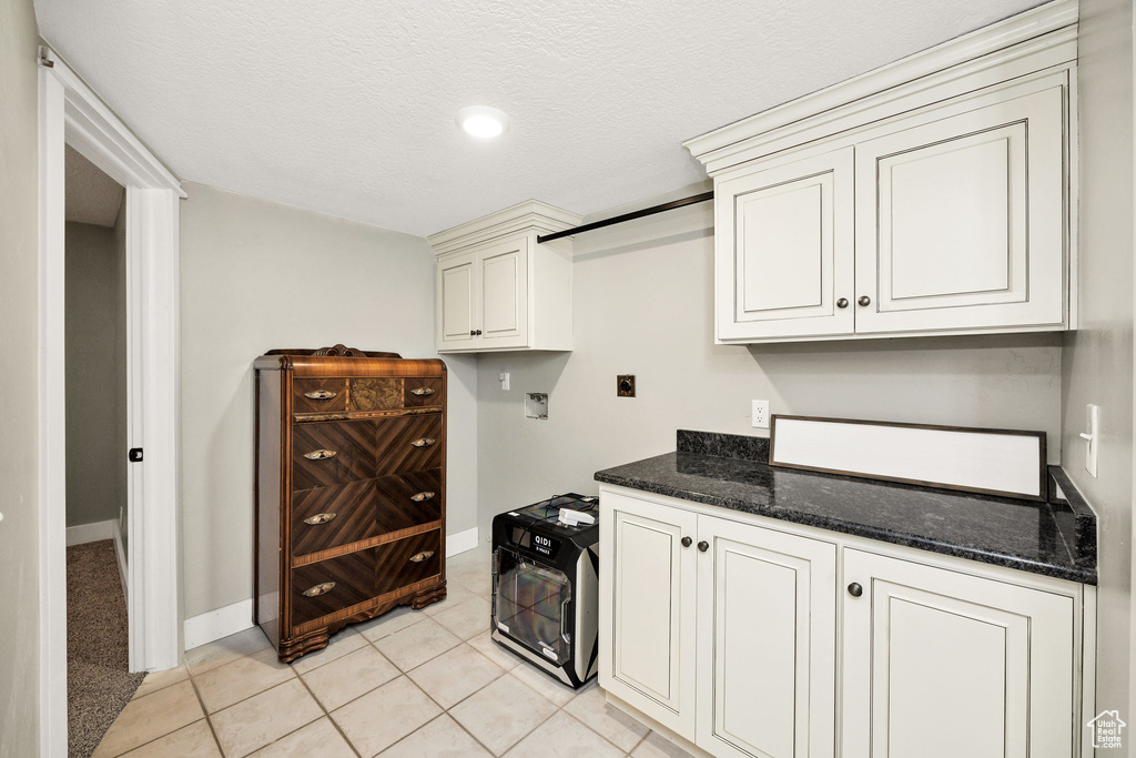 Kitchen with baseboards, dark stone countertops, and light tile patterned flooring
