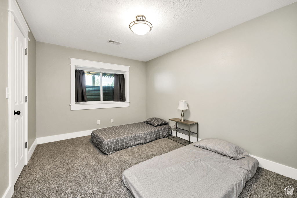 Carpeted bedroom with baseboards and a textured ceiling
