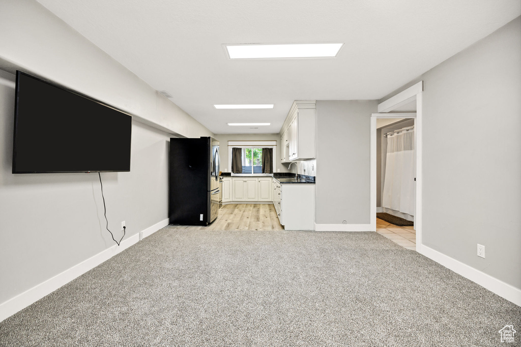 Unfurnished living room featuring light carpet and baseboards