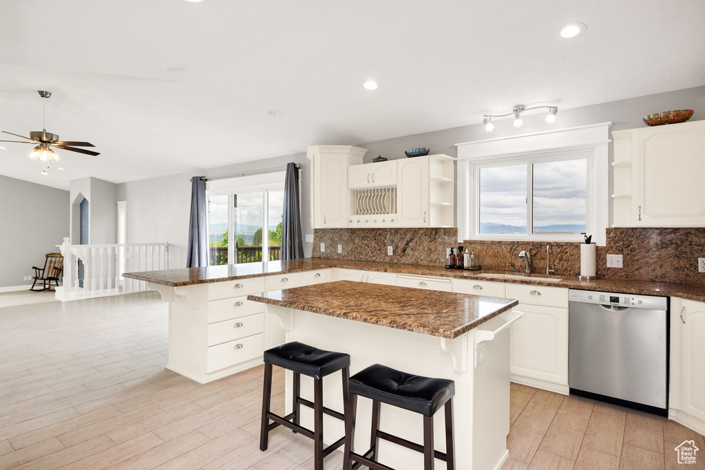 Kitchen with stainless steel dishwasher, open shelves, a peninsula, a breakfast bar, and tasteful backsplash