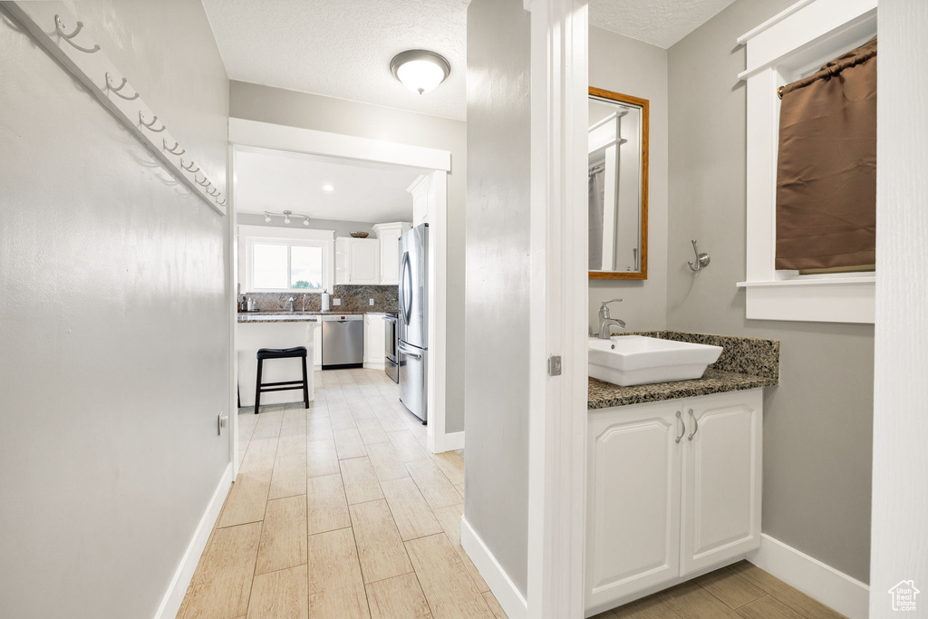Corridor featuring a sink, light wood finished floors, and baseboards