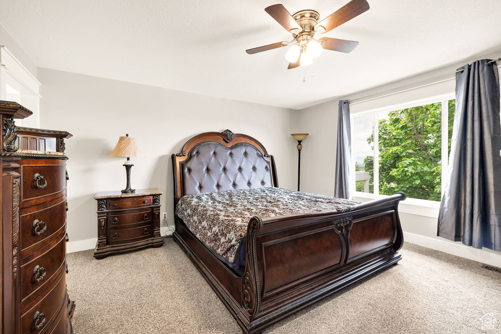 Bedroom with light colored carpet, baseboards, and a ceiling fan