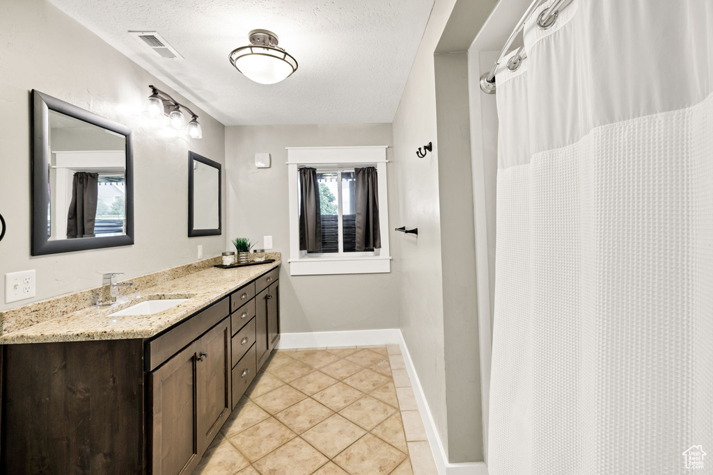 Full bathroom featuring tile patterned floors, vanity, a textured ceiling, and baseboards