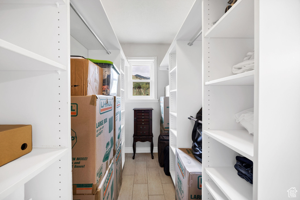 Walk in closet with light wood-style flooring