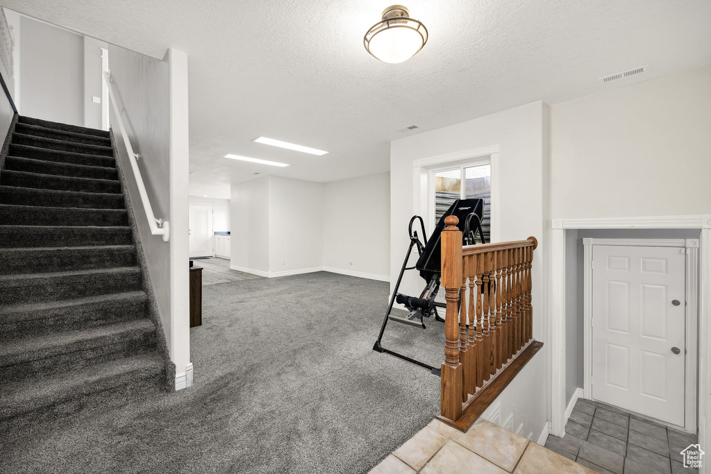 Stairway featuring baseboards, carpet floors, and a textured ceiling