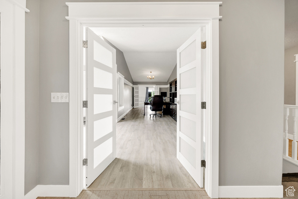 Hallway with a desk, light wood-type flooring, and lofted ceiling