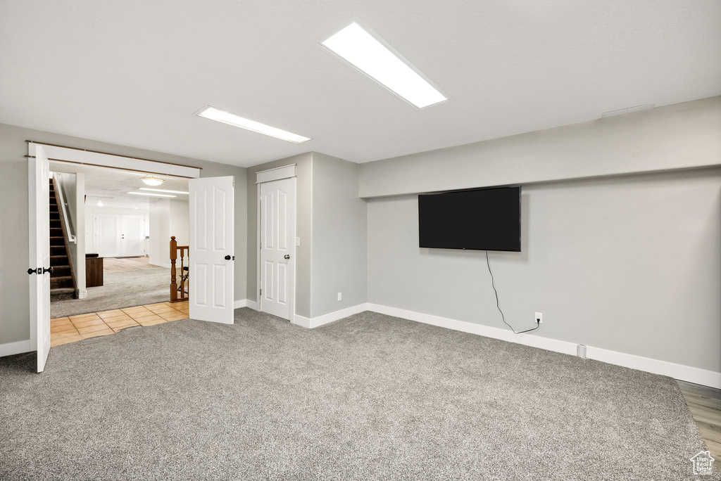 Finished basement featuring carpet, baseboards, stairs, and tile patterned flooring