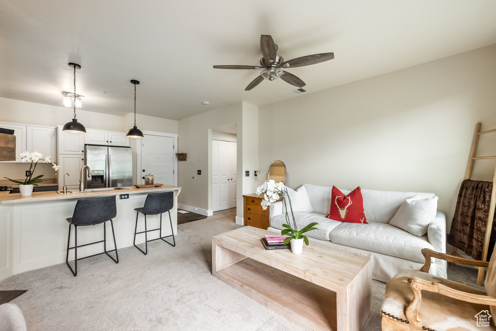 Living room with a ceiling fan and light carpet