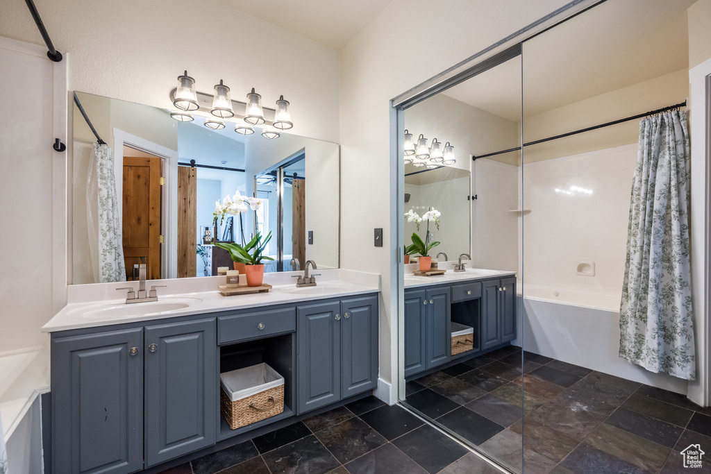 Full bath with shower / tub combo, double vanity, and stone finish flooring
