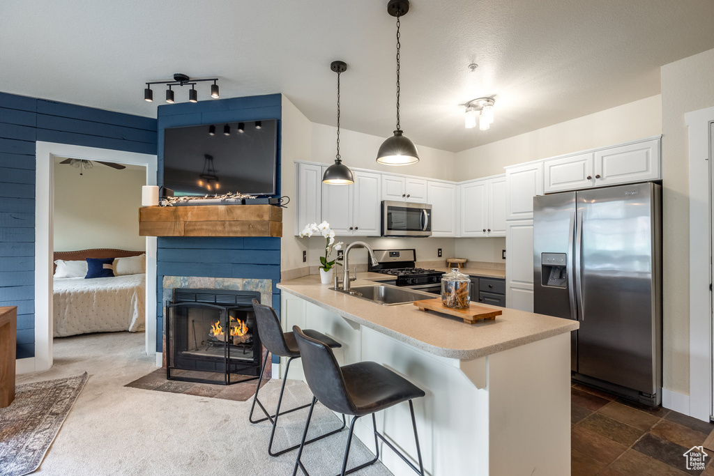 Kitchen with appliances with stainless steel finishes, a peninsula, light countertops, a kitchen breakfast bar, and white cabinetry