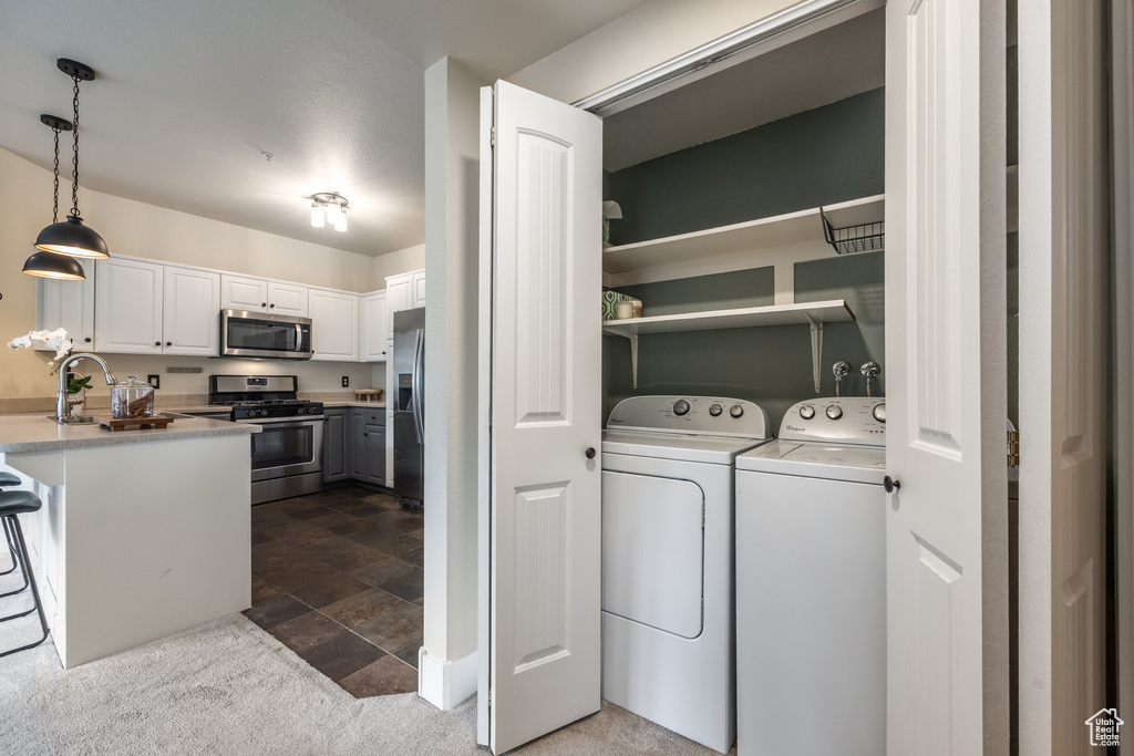 Laundry room with washer and clothes dryer and dark stone finish flooring