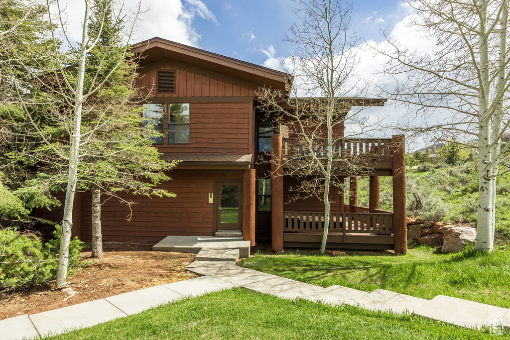 View of front of house featuring a wooden deck and a front yard