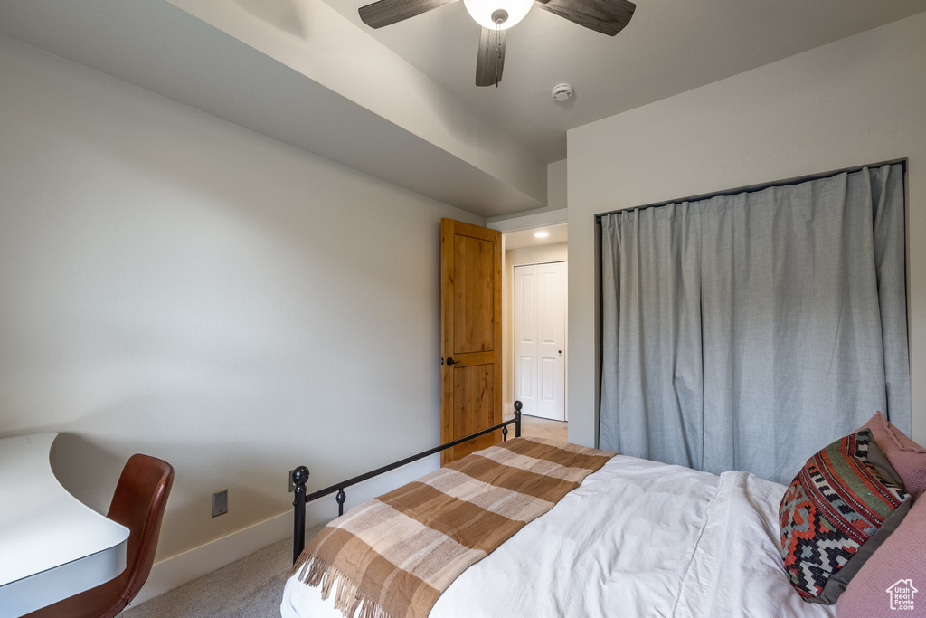 Bedroom with light colored carpet, baseboards, and a ceiling fan