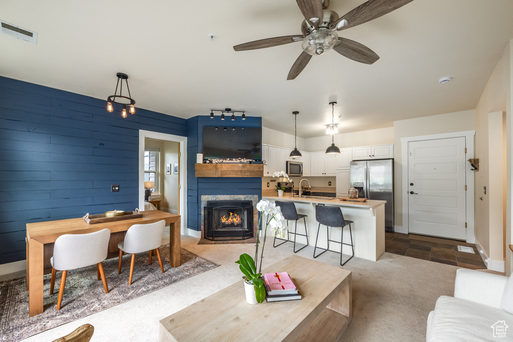 Living area featuring a fireplace with flush hearth, a ceiling fan, and light carpet