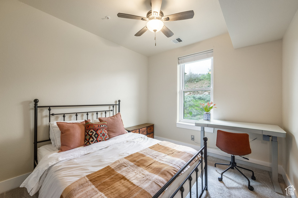 Bedroom featuring light carpet, baseboards, ceiling fan, and an office area