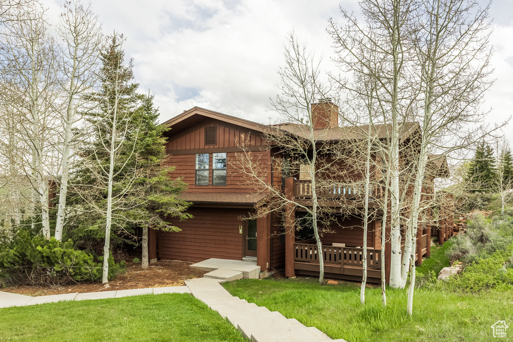 View of front of home featuring a chimney, a front yard, and a deck