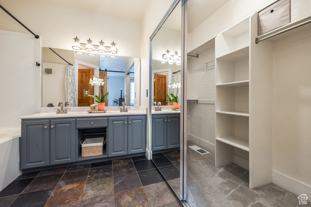 Bathroom with double vanity, curtained shower, and stone finish floors