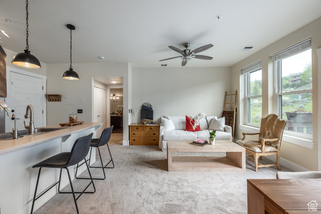 Living area featuring light colored carpet and ceiling fan