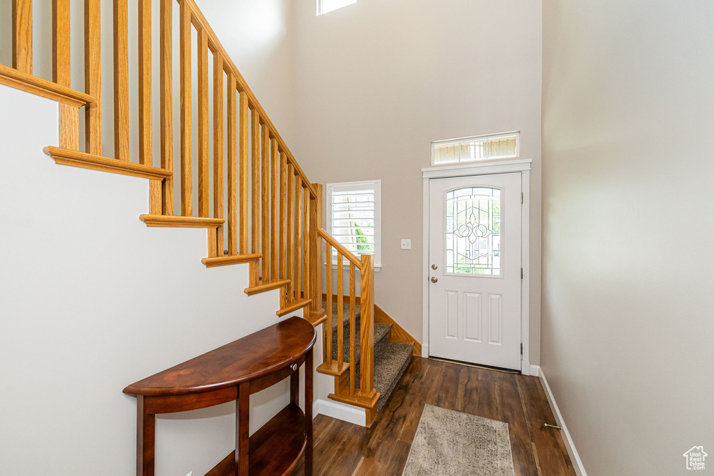 Entrance foyer with stairway, wood finished floors, a high ceiling, and baseboards