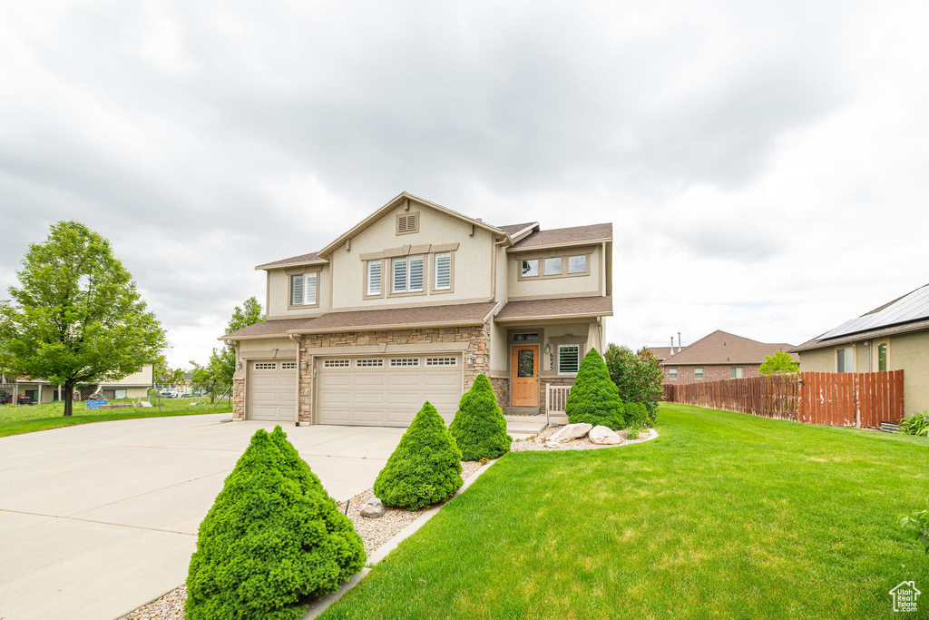 View of front of house with an attached garage, driveway, stone siding, and stucco siding