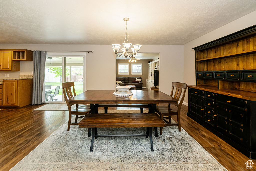Dining space featuring dark wood-style floors and a chandelier