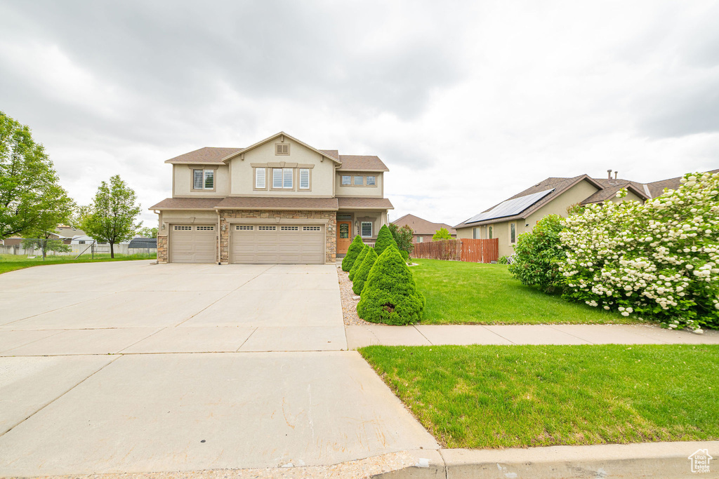 View of front of home with an attached garage, concrete driveway, stucco siding, and stone siding