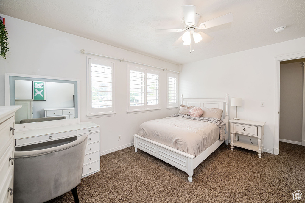 Bedroom featuring dark carpet, baseboards, and ceiling fan