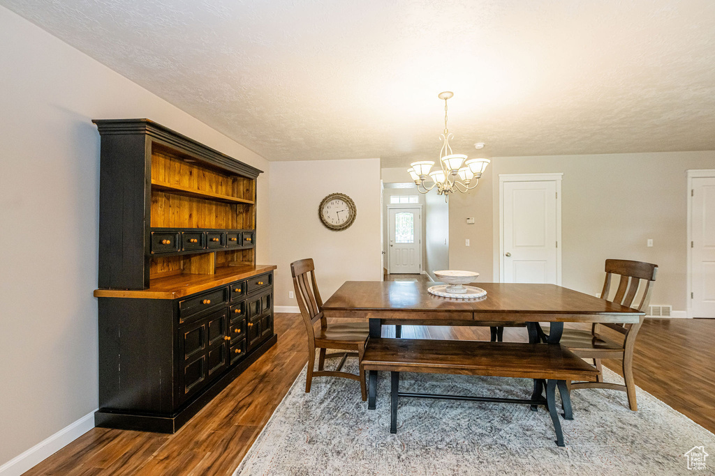 Dining space featuring a chandelier, baseboards, and dark wood-style floors