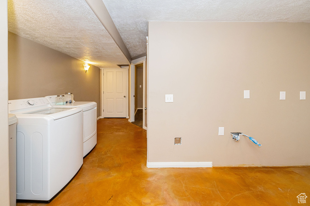 Laundry area featuring a textured ceiling, independent washer and dryer, and baseboards