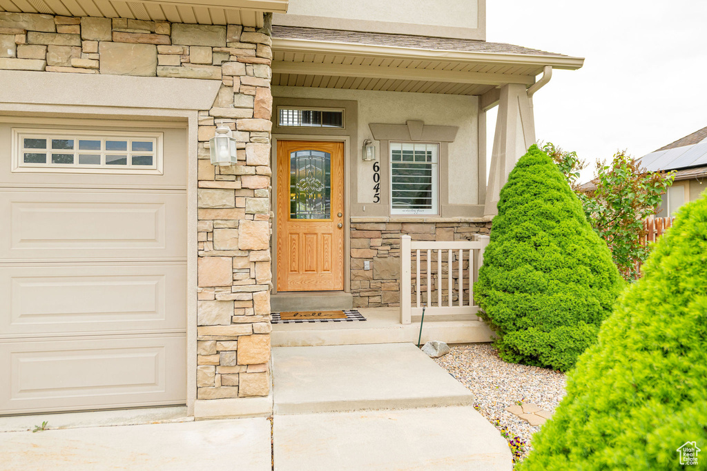 Doorway to property with stone siding, stucco siding, and covered porch