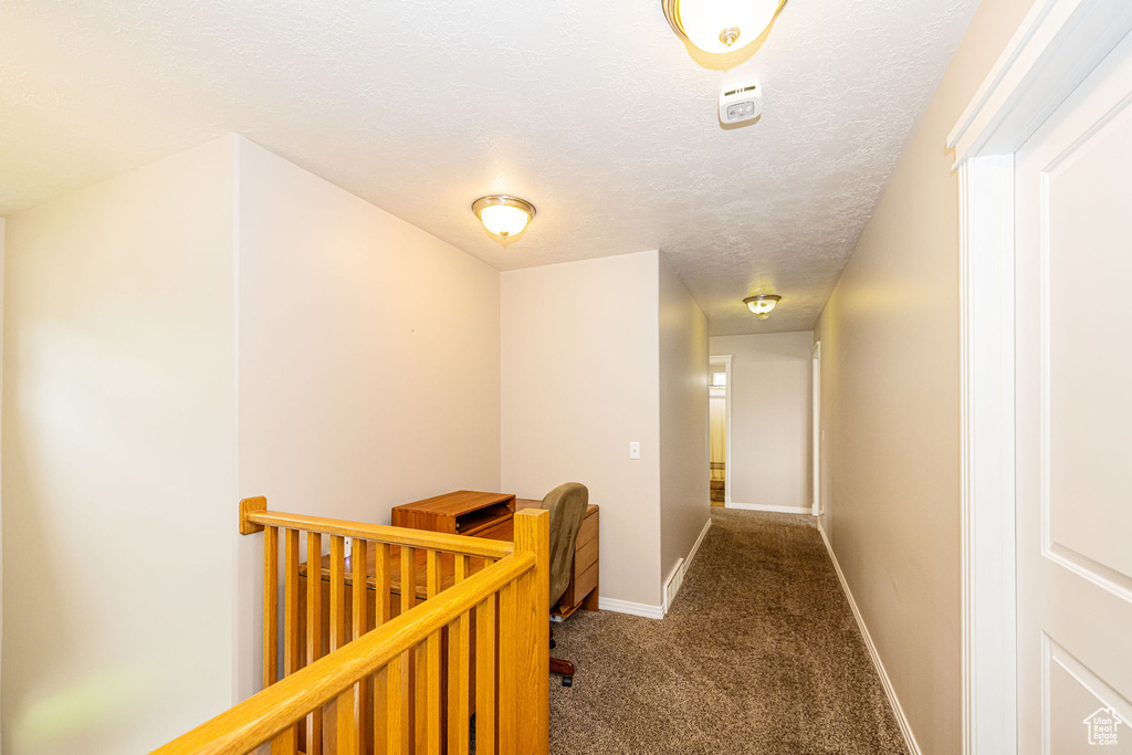 Corridor with an upstairs landing, carpet, baseboards, and a textured ceiling