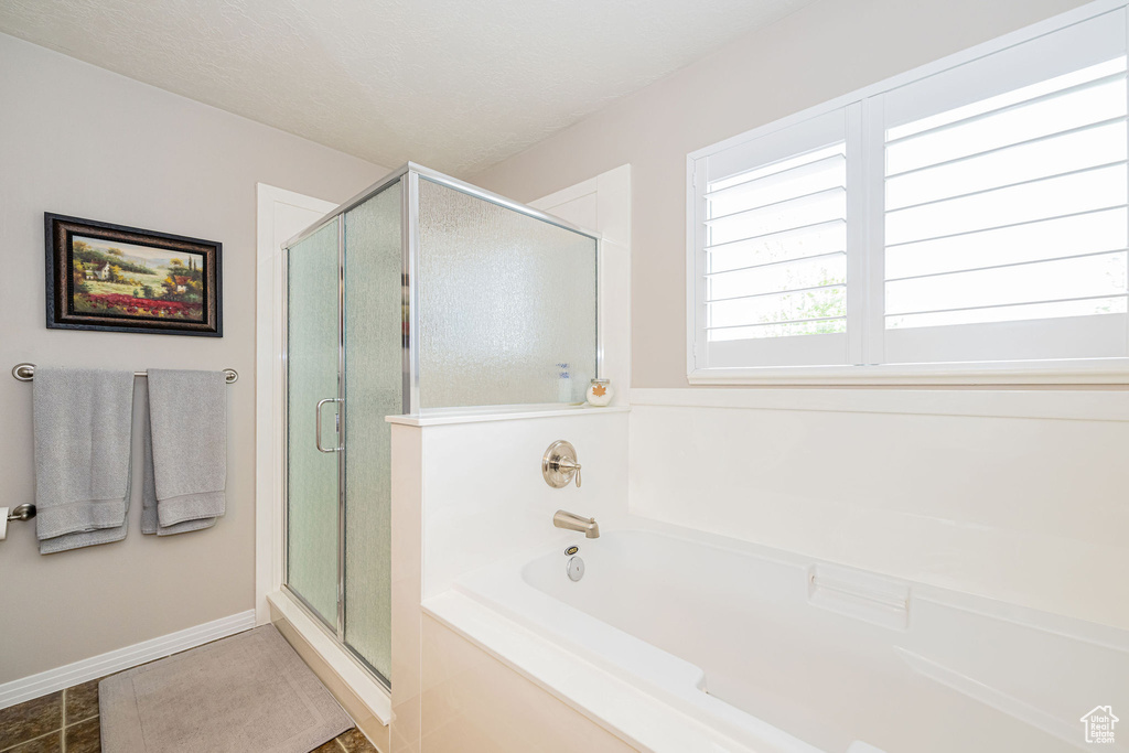 Bathroom featuring a stall shower, a garden tub, baseboards, and tile patterned floors