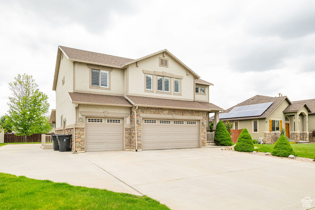 View of front of property with stone siding, a garage, stucco siding, and concrete driveway