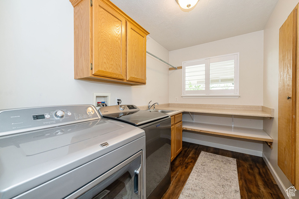 Laundry room featuring cabinet space, independent washer and dryer, dark wood-type flooring, and baseboards