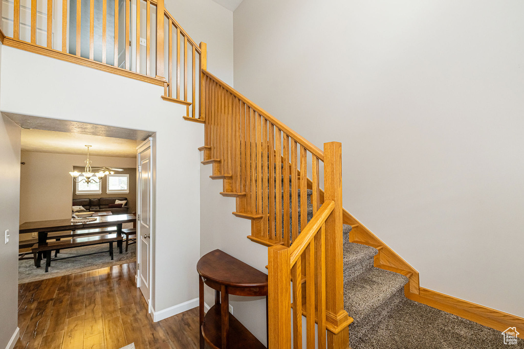 Stairs with a chandelier, wood finished floors, and baseboards
