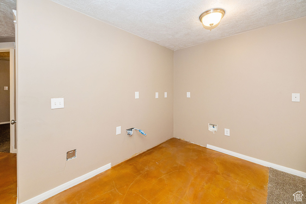 Spare room with a textured ceiling, baseboards, and light carpet