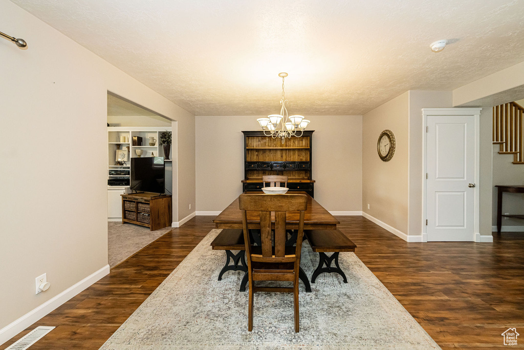 Dining space featuring stairs, a chandelier, dark wood-style floors, and baseboards