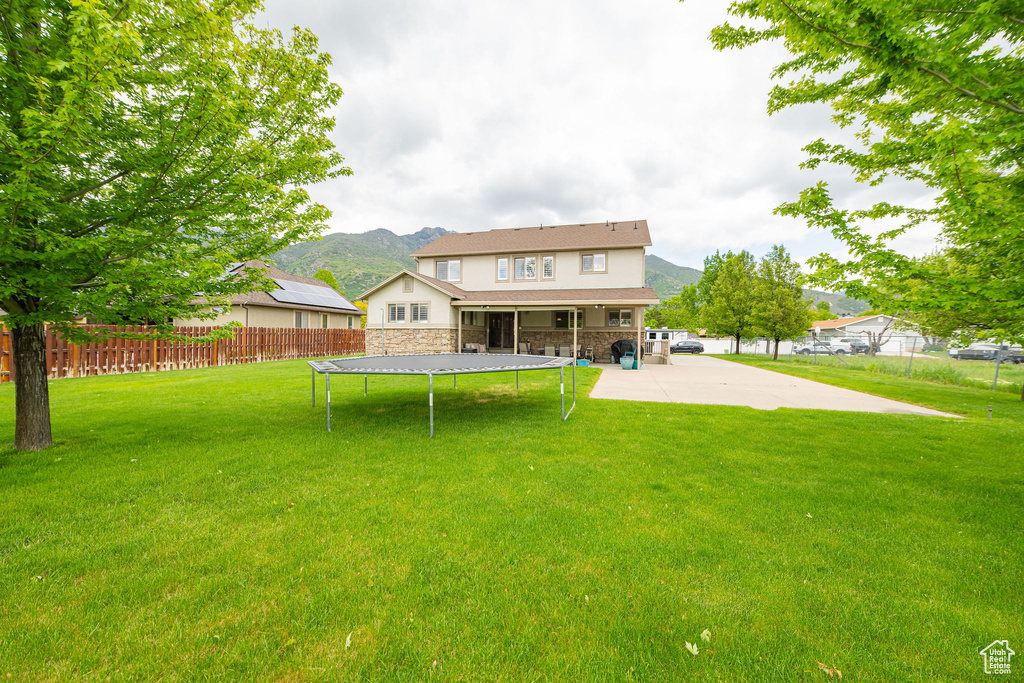 Rear view of property featuring a trampoline, a mountain view, stone siding, and stucco siding