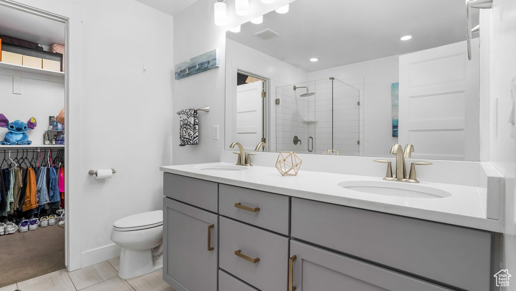 Bathroom with a shower stall, toilet, double vanity, recessed lighting, and baseboards