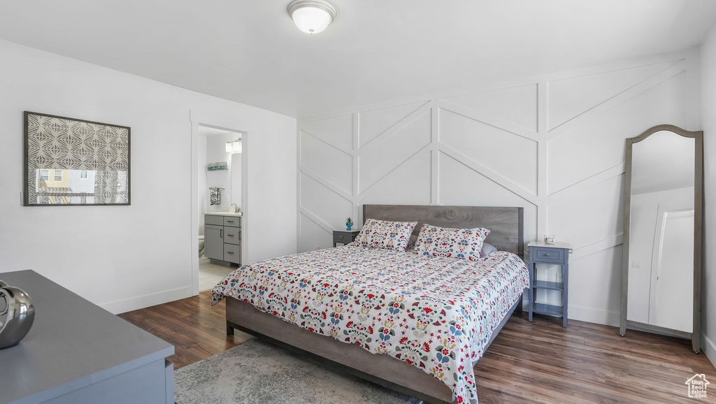 Bedroom featuring wood finished floors, baseboards, and ensuite bathroom