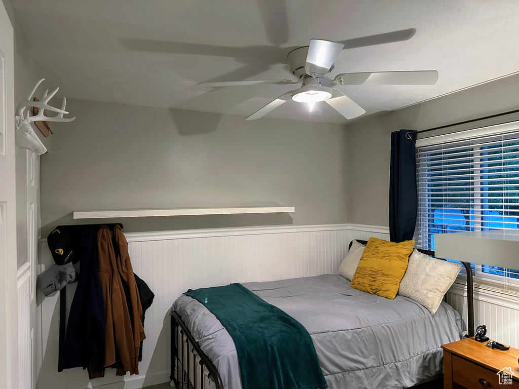 Bedroom featuring a wainscoted wall and ceiling fan