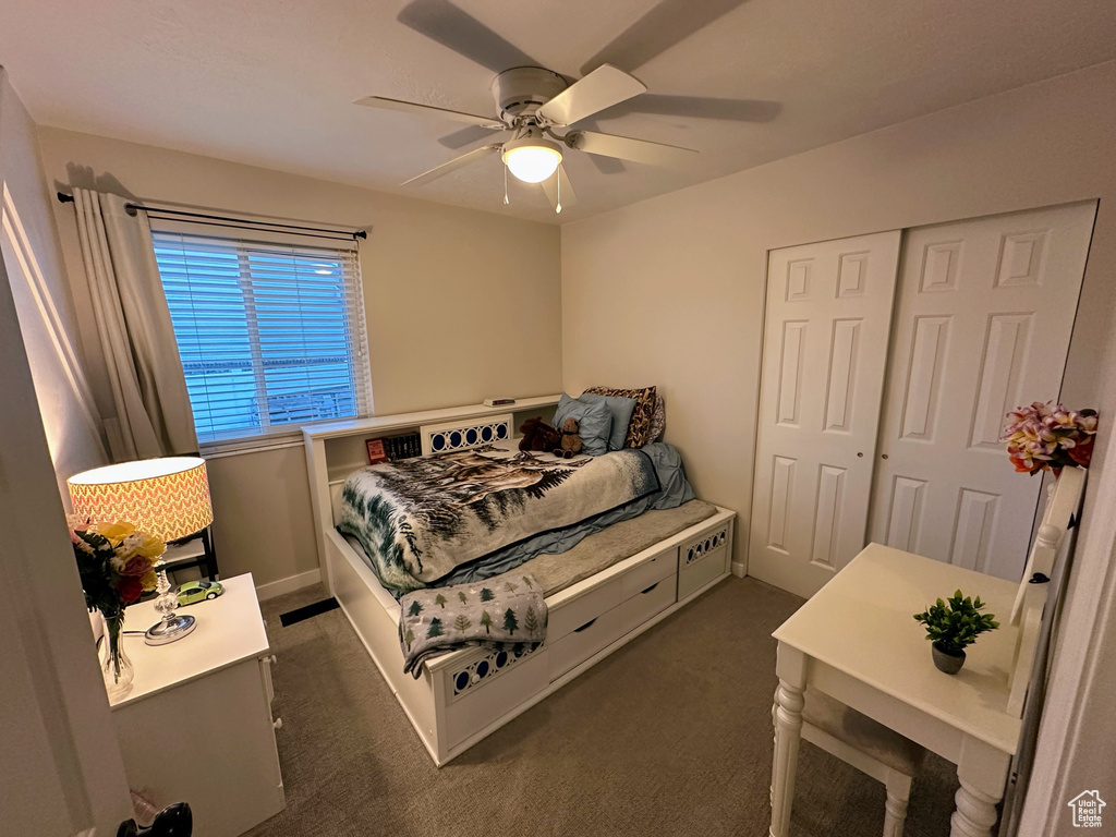 Bedroom with dark carpet, a closet, ceiling fan, and baseboards